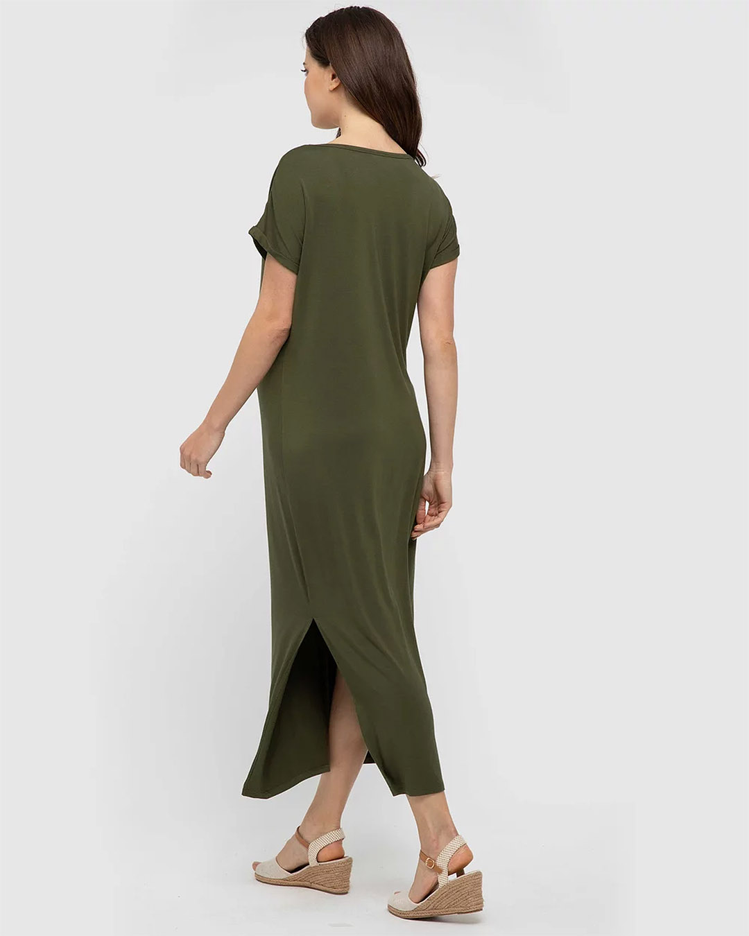 A pregnant woman wears a dark green bamboo jersey ankle-length dress with a side split. 