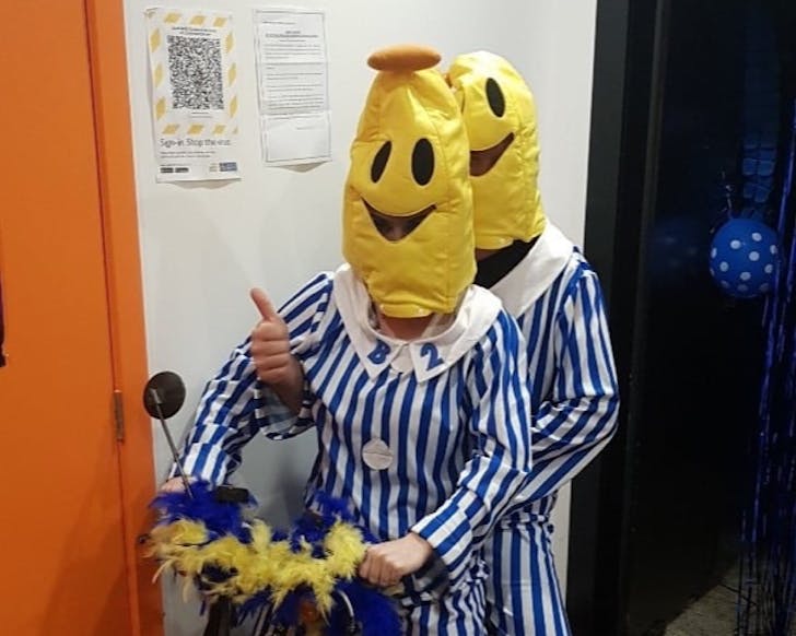 Two people riding a mobility scooter dressed in Bananas In Pajamas costumes. 