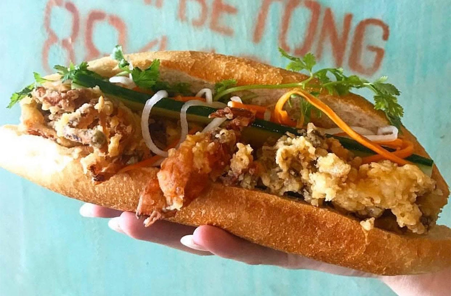 Someone holds a stuffed Banh mi from Banh Mi Caphe, one of the best cheap eats you can get in Hamilton.