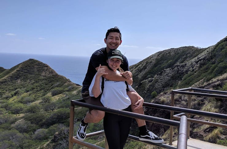 Two people hugging with view of mountains and sea behind them