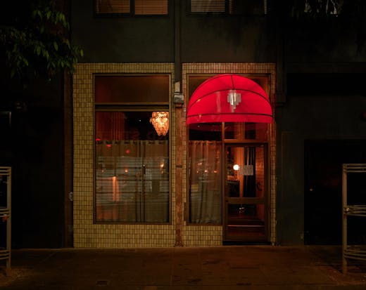 The outside of a bar with lights on inside. 
