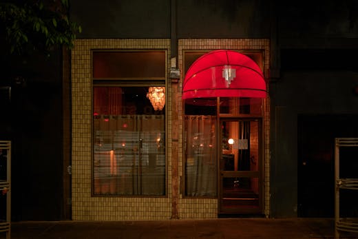 The outside of a bar with lights on inside.