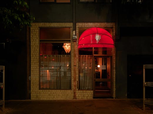 The outside of a bar with lights on inside. 