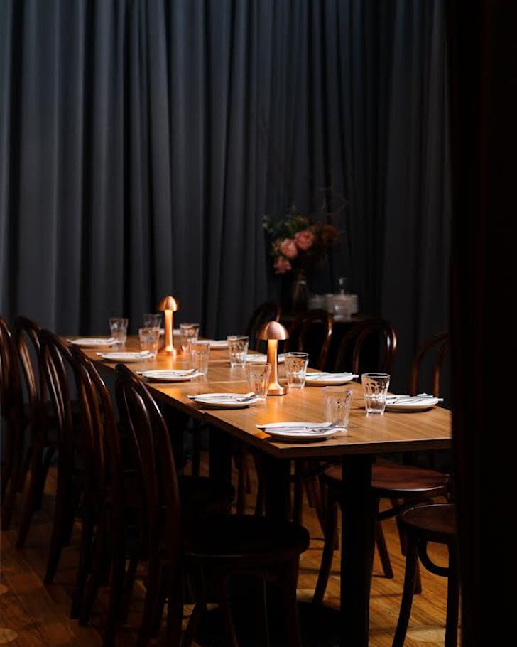 A curtained private dining room with a bunch of pretty flowers in the back corner.