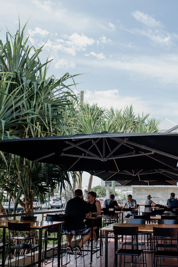 a cafe terrace flanked by leafy trees
