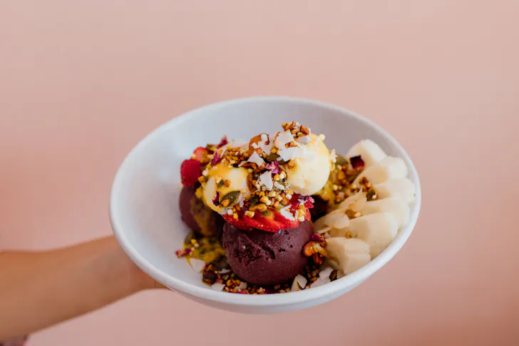 someone holding an ornate gelato dessert against a salmon pink wall