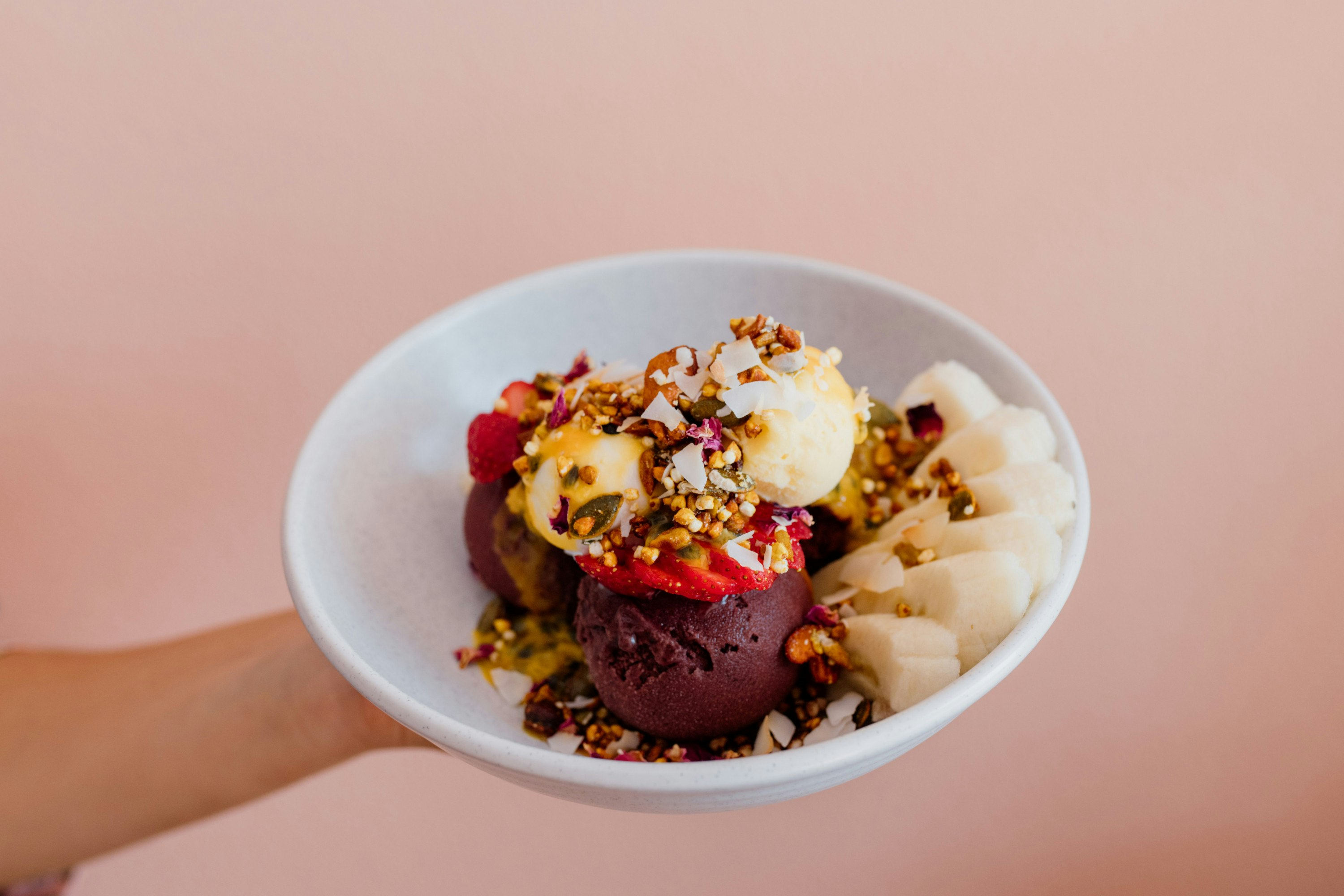 someone holding an ornate gelato dessert against a salmon pink wall