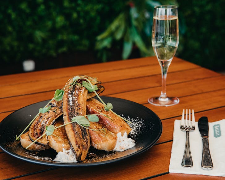 A plate of decadent French toast and a glass of bubbles sit on a table at Basaltâs bottomless brunch.