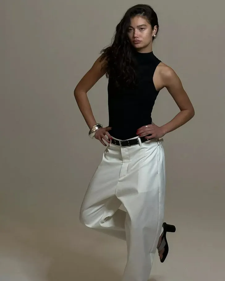 A woman in a black top of white pants from Bassike one of the best Australian fashion labels