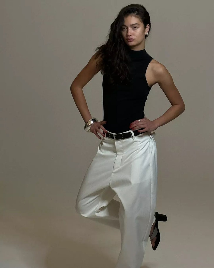A woman in a black top of white pants from Bassike one of the best Australian fashion labels