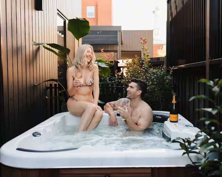 A couple is pictured in the hot tub at Bayside Villa one of the best Airbnbs in Adelaide