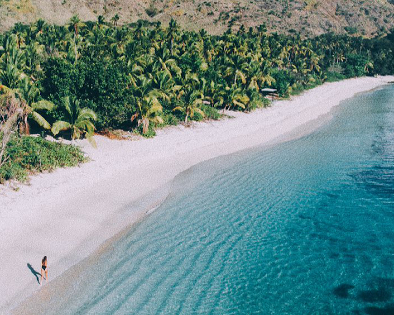 A woman walks along a beautiful beach at Vomo Fiji Resort. 
