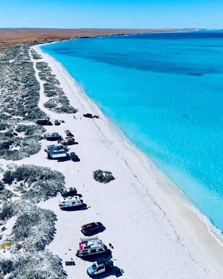 Beachside camping with vehicles.