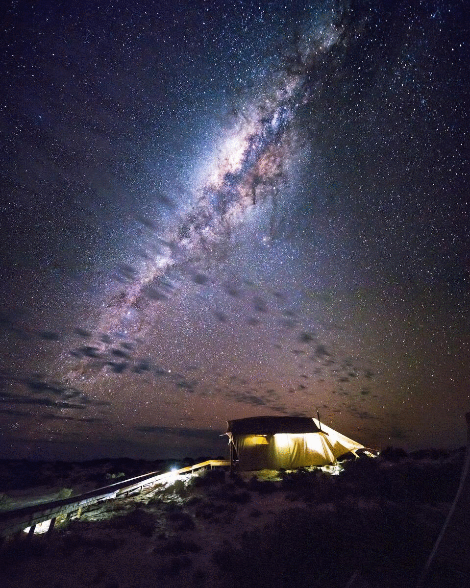 A safari-style tent looks insignificant against a dreamy canopy of stars.