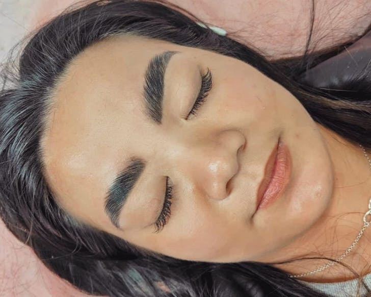 Woman laying with eyes closed with freshly done eyelash extensions