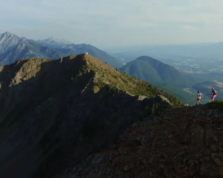 Two people run along a stunning ridgeline. 