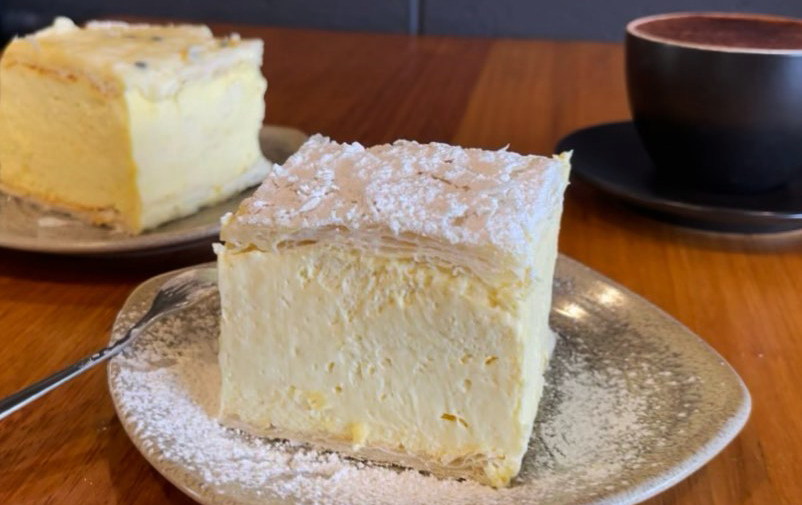 A thick square of vanilla slice on a plate with icing sugar, a best vanilla slice Melbourne option. 