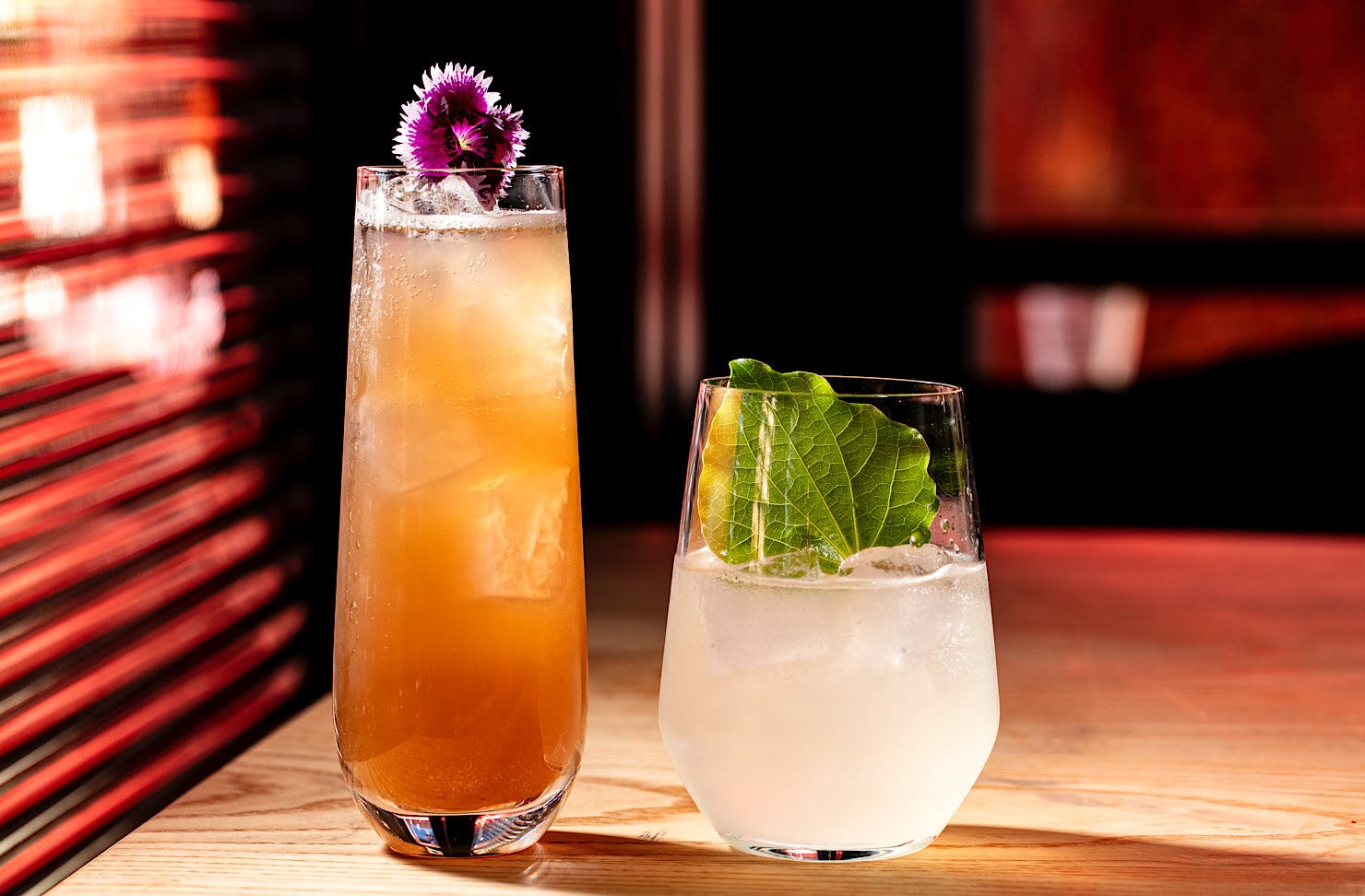 A tall orange cocktail sits beside a short lemonade-hued cocktail at Bedford Soda & Liquor. 