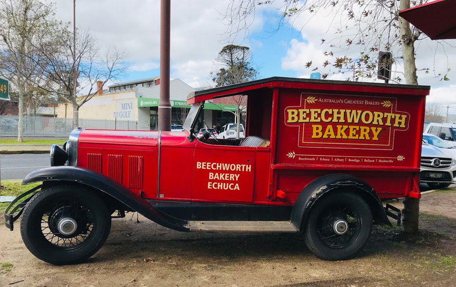 An antique red car next to Beechworth Bakery in Echuca. 