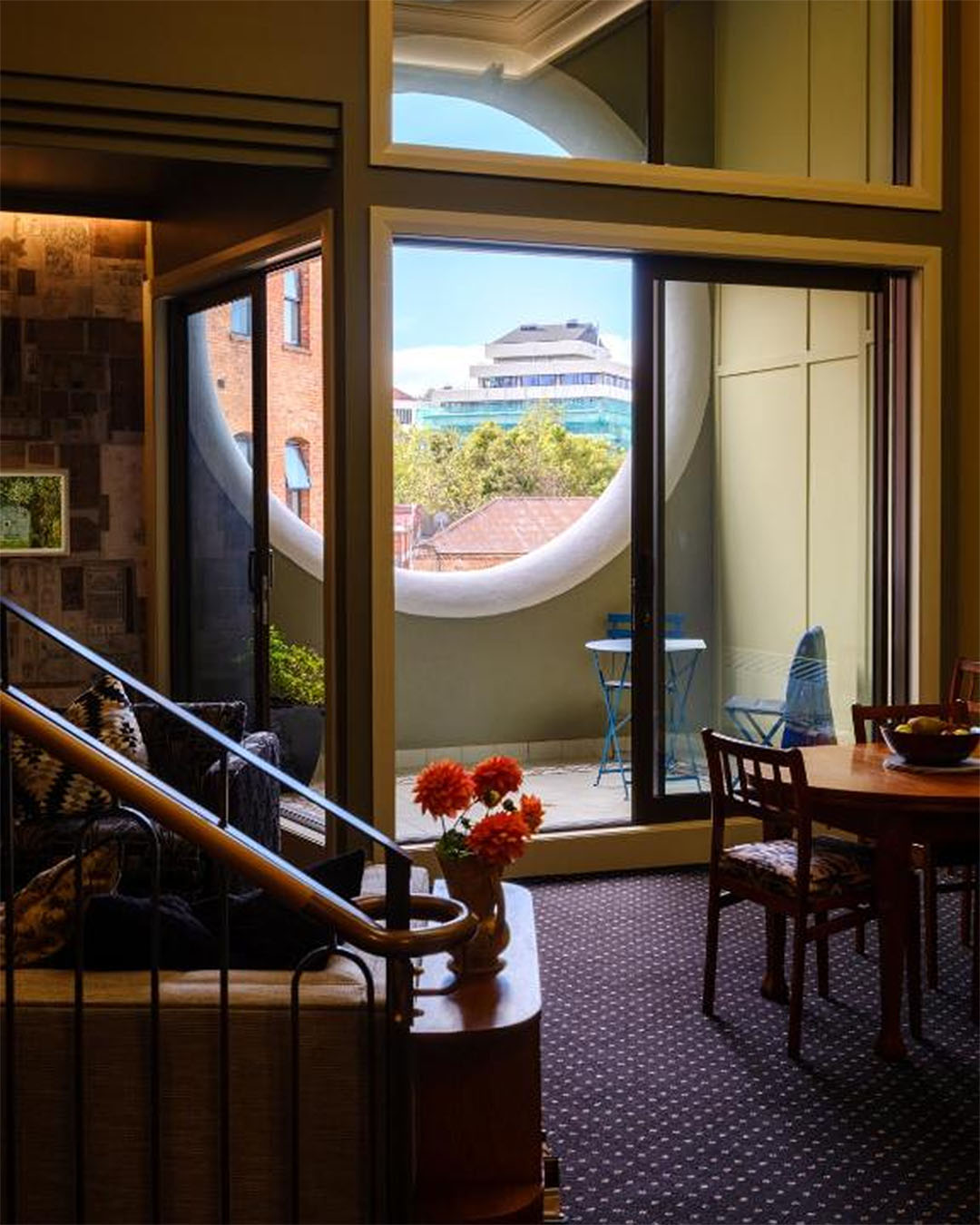 Classic wooden accents and floor to ceiling windows give out onto another oval window and the blue sky behind at Bell Hill Apartments in Dunedin.