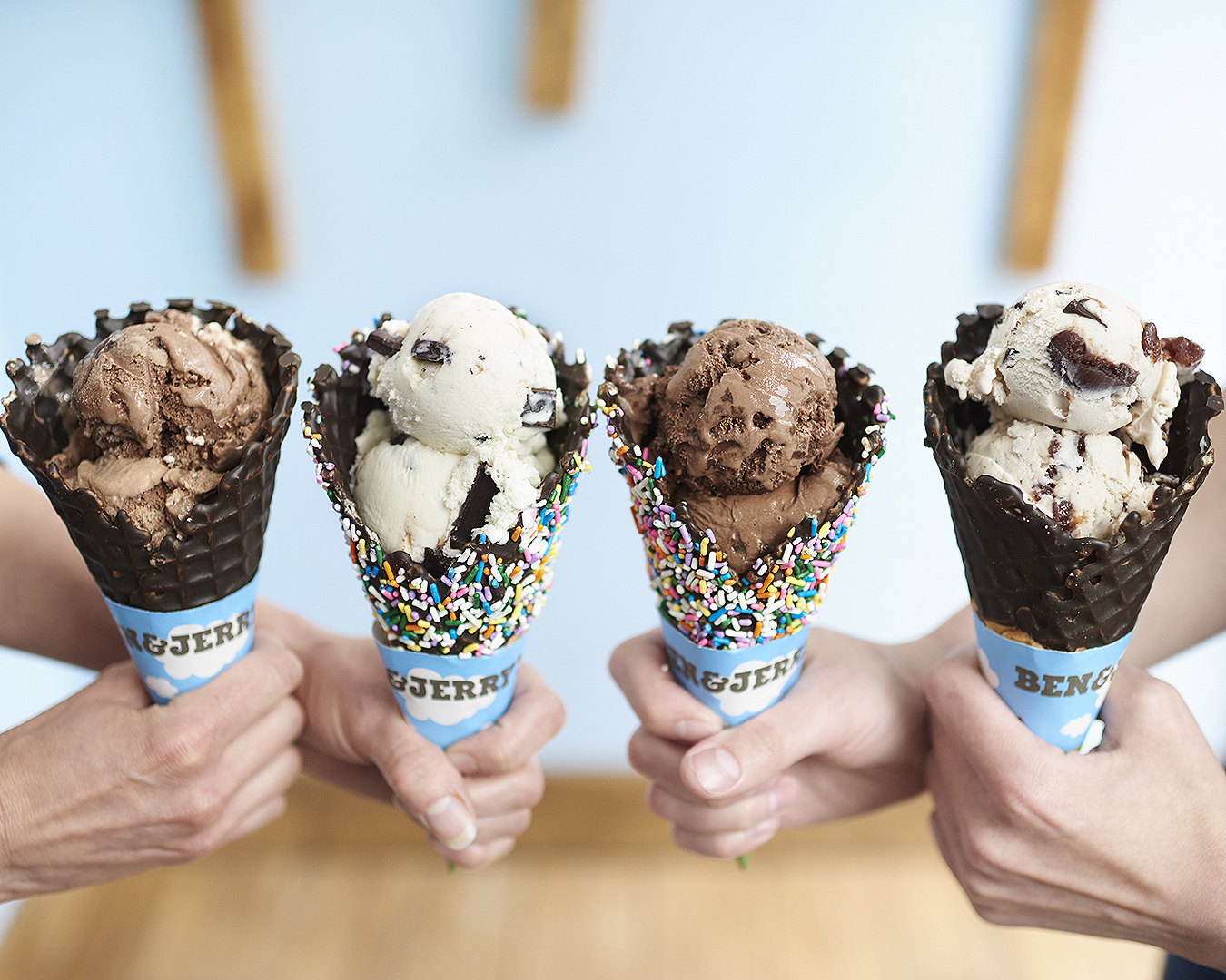 Four cones of delicious Ben & Jerry's ice cream is held aloft.
