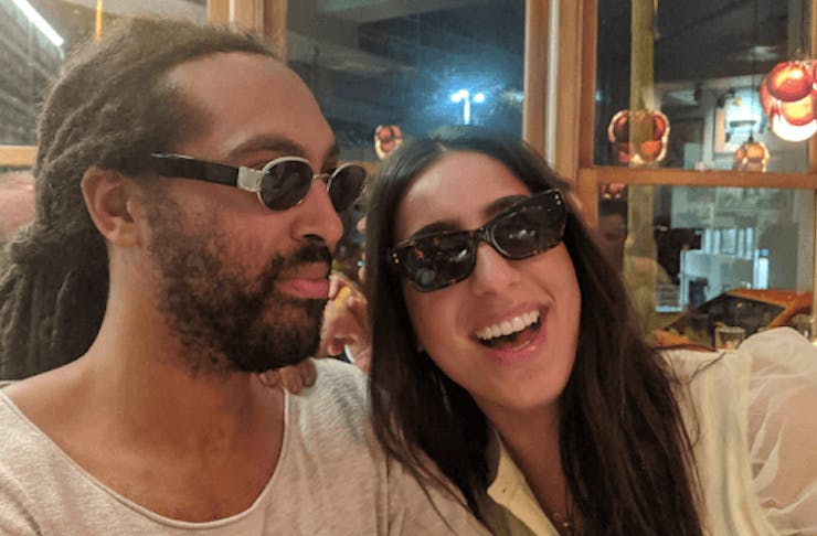 Two people wearing sunglasses smiling.