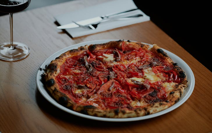 A pizza and glass of wine on a table at a best italian restaurant Melbourne. 