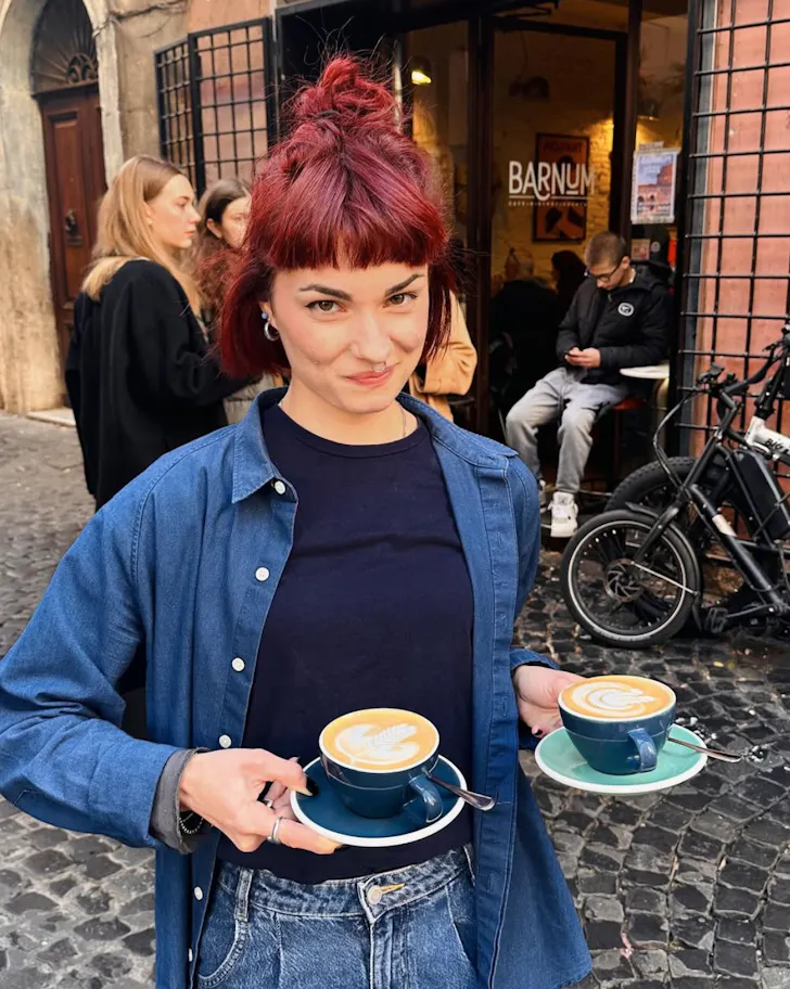 Best coffee spots in Rome  Barnum Cafe with someone holding two cappuccinos in a Roman street set against the backdrop of the cafÃ© shopfront