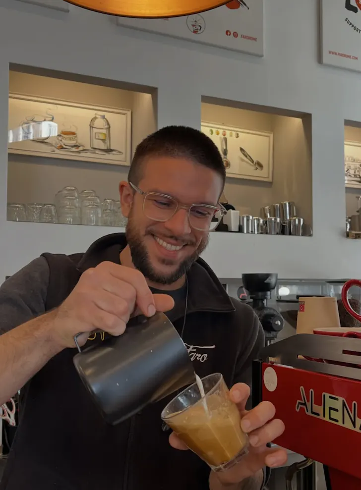 Best coffee spots in Rome at Faro with a barista pouring milk into a coffee and an Aliena coffee machine in the background