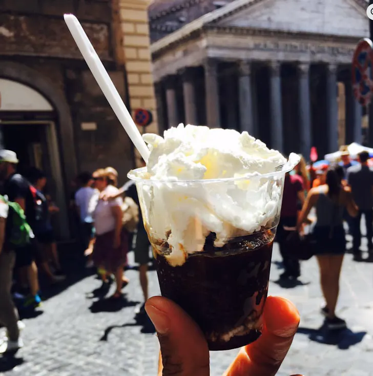 Coffee in Rome at La Casa del CaffÃ¨ Tazza d'Oro with a coffee granita topped with whipped cream being held up in front of the Pantheon