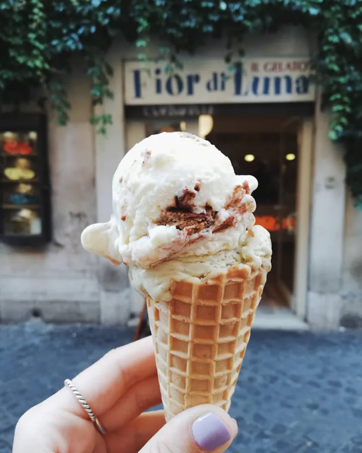 Best gelato in Rome from Fiordiluna with tiramisu and pistachio scoops in a waffle cone with the shopfront in the background