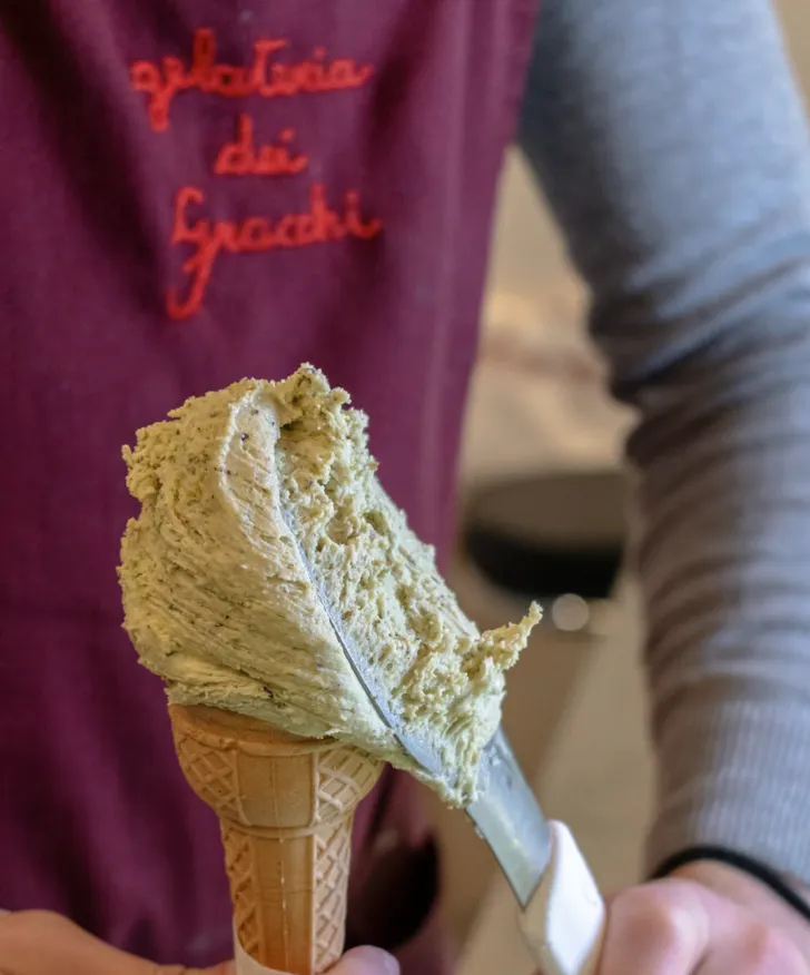 One of the best gelato shops in Rome, Gelateria dei Gracchi scooping pistachio gelato into a cup