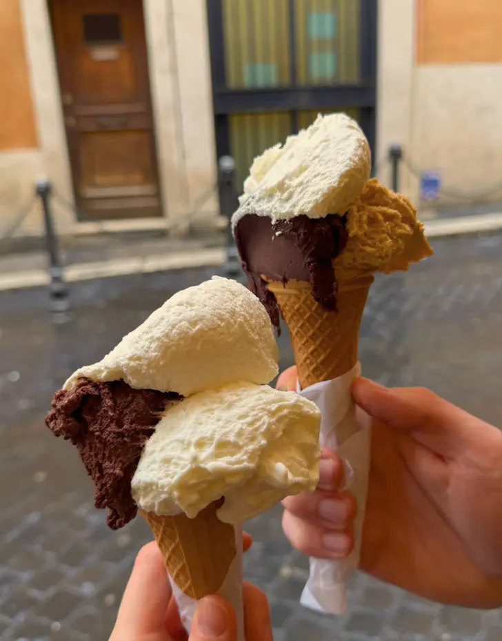 Best gelato in Rome from Giolitti with chocolate and cream scoops in waffle cones on cobblestone street
