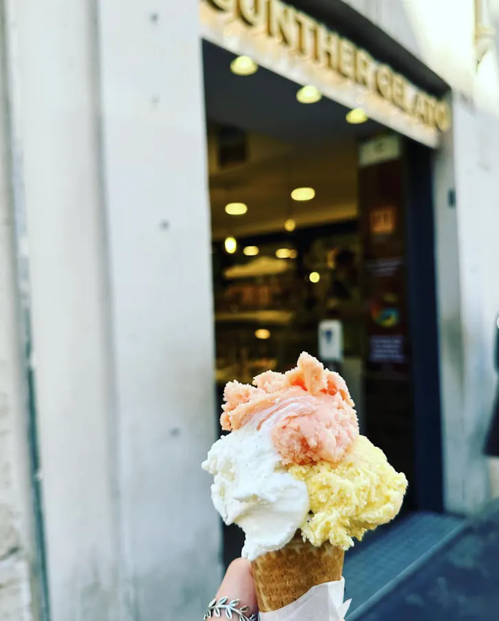 Best gelato in Rome from Gunther Gelato with a triple scoop of peach, cream and mango in a waffle cone