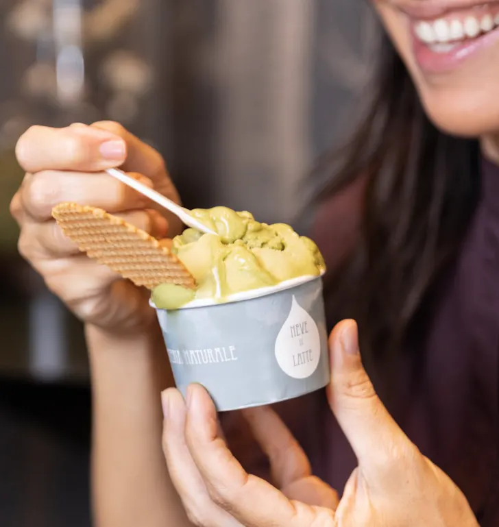 Best gelato in Rome from Neve di Latte with a scoop of pistachio in a cup topped with a waffle biscuit