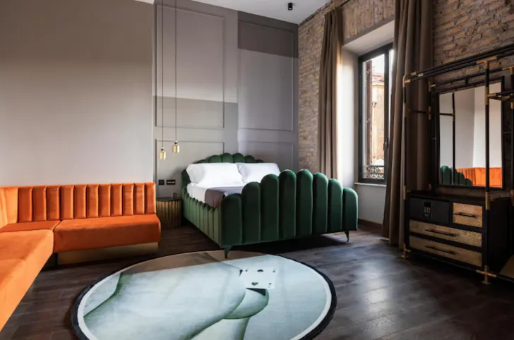 Best hotels in Rome at Chapter Roma with bold bedroom design, velvet bed and exposed brick wall