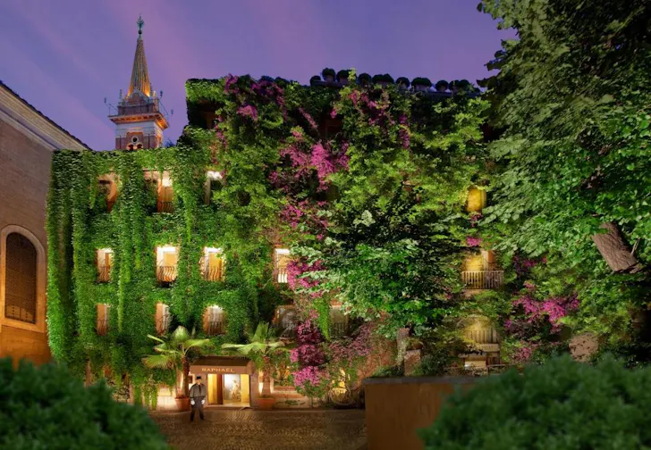 Best rooftop hotels in Rome at Hotel Raphael with vine covered building and illuminated evening exterior