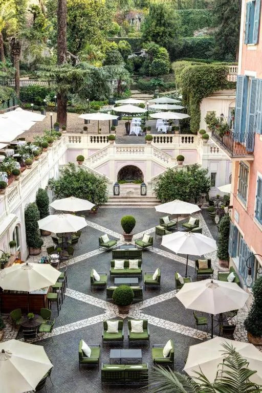 A luxury hotel in Rome's scenic outdoor courtyard filled with sun umbrellas, lounges and greenery