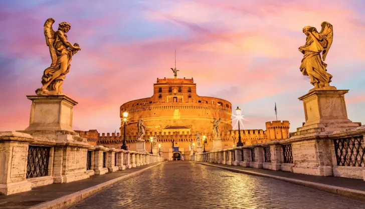 Castel SantâAngelo in Rome at sunset viewed from Ponte SantâAngelo with angel statues lining the bridge