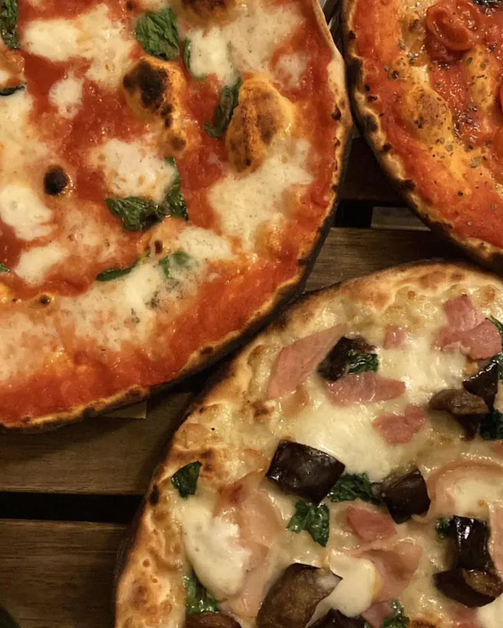The best pizza in Rome at Pizzeria Alle Carette with thin and crispy pizzas â one margherita and one with ham and mushrooms