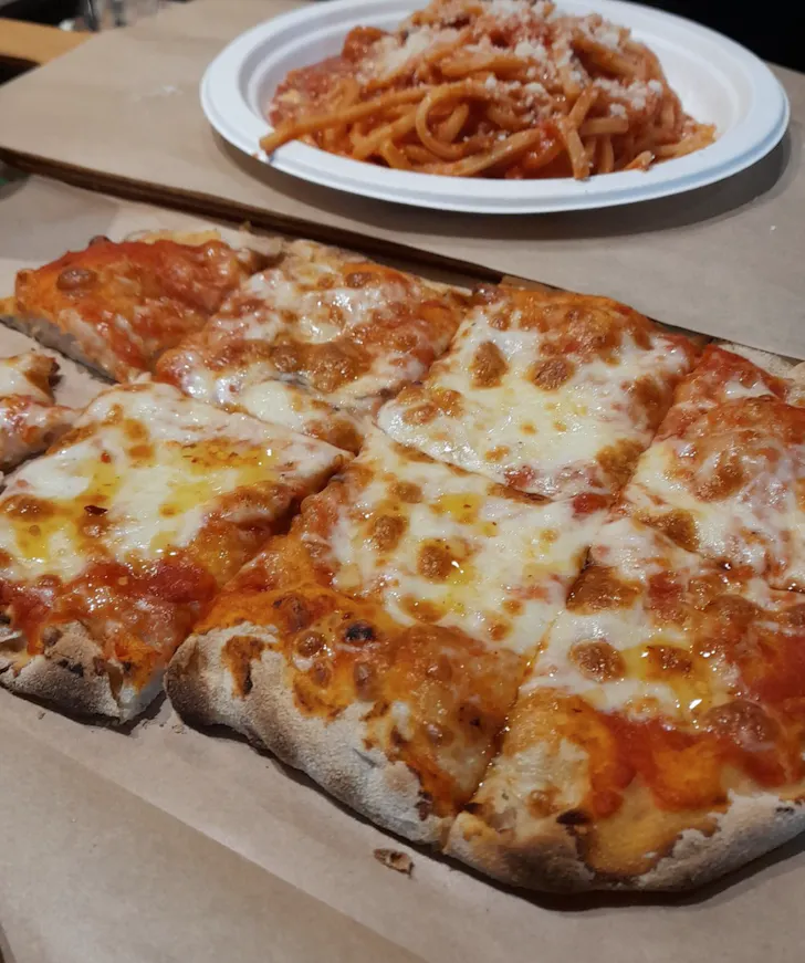 Best pizza in Rome at Pinsitaly Trevi with a rustic rectangular pinsa style margherita pizza and a bowl of spaghetti 