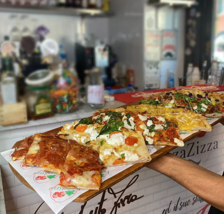 Best pizza in Rome at Pizza Zizza with square slices of pizza topped with seasonal ingredients on a wooden platter
