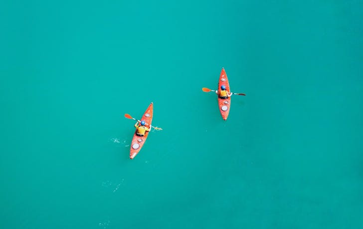 Drone shot of two people kayaking on turquoise blue water