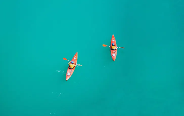 Drone shot of two people kayaking on turquoise blue water