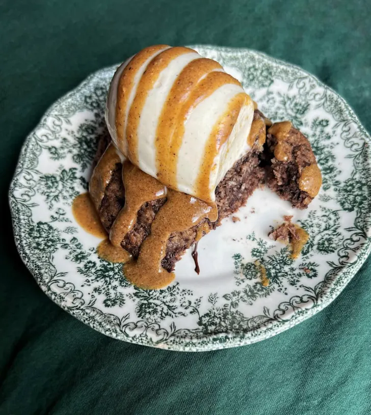 Best restaurants in Rome at Barred with a cake, vanilla ice cream and caramel sauce sitting on an antique style green patterned plate on a dark green background