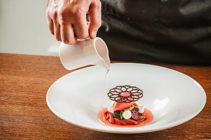 Best restaurants in Rome at Moma with a delicately plated dessert and sauce being poured over
