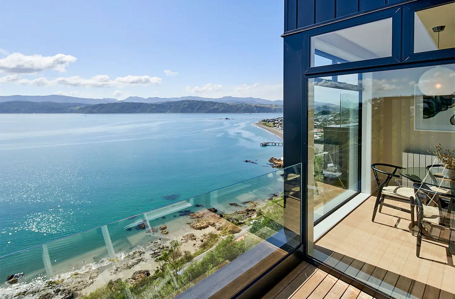 A peek from the balcony into the living area of the Harbour View Home shows off a marble countertop, stylish seating, and incredible sea views. Definitely one of the best Airbnbs in Wellington.
