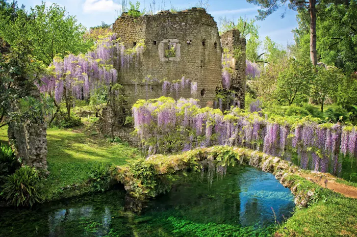 Best day trips from Rome at Garden of Ninfa with medieval ruins, stone bridge and wisteria over a clear river