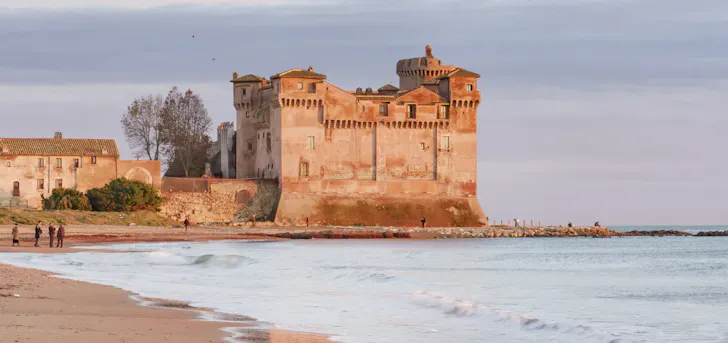 Best day trips from Rome in Santa Severa with a long, sandy stretch of beach and a 14th-century castle in the background