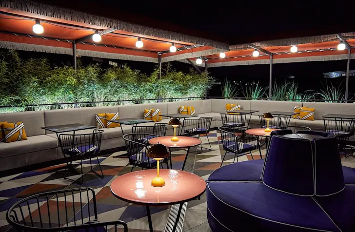 Best rooftop bars in Rome at Paparazzo Rooftop with a retro, glamorous outdoor dining area lit up at night